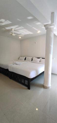 a large bed in a white room with pillars at RJ14 Accommodations at Baga Beach in Baga