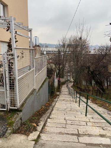 a stone sidewalk next to a building with a fence at Apartment Kalemova in Sarajevo