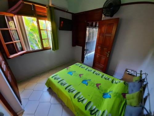 a bedroom with a bed with a green comforter at Le Coin Tranquille in Sainte-Anne