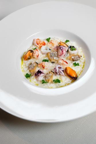a white bowl of seafoodowder on a white plate at Hotel Locanda Al Piave ***S in San Donà di Piave