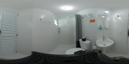 bagno bianco con servizi igienici e lavandino di Urbano Suítes a Ubatuba