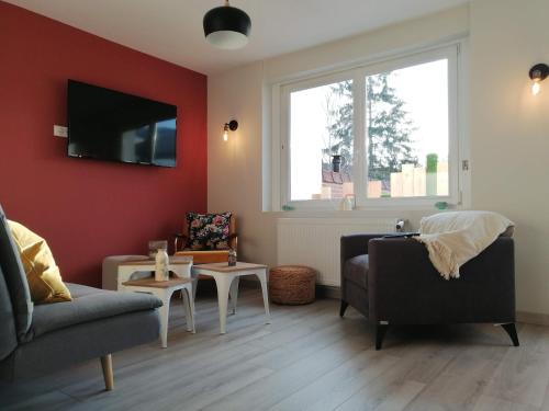 een woonkamer met een bank en een tv aan de muur bij Maison avec garage, terrasse, l'Herboristerie in Béthune