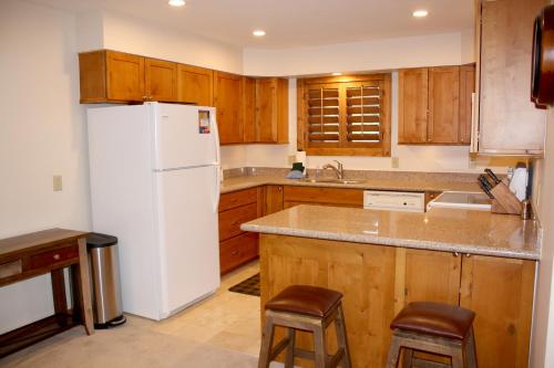 a kitchen with a white refrigerator and wooden cabinets at Woods Manor #302-A - Close to Main Street - Access to Indoor Hot Tub and Shuttle in Breckenridge