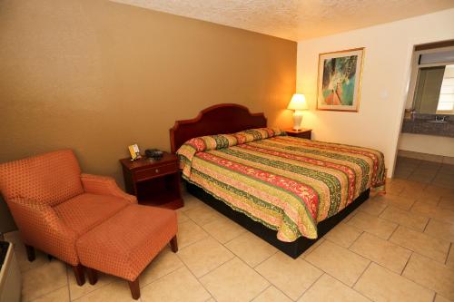 um quarto com uma cama e uma cadeira em Texas Inn Beaumont em Beaumont