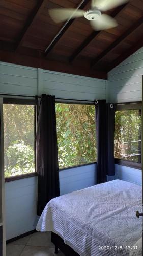 a bedroom with two windows and a bed in it at Barra Beach Club CASAS in Florianópolis
