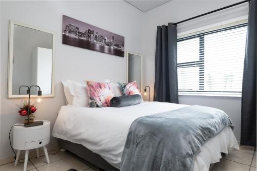 a white bedroom with a large bed and a window at Ballito Luxury Apartment in Ballito