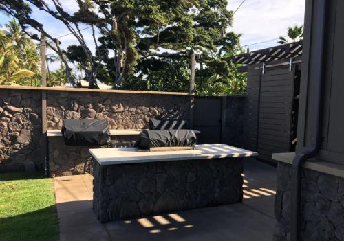 a patio with a bench and a stone wall at 9B EKAHI VILLAGE-STUDIO BATH, GARDEN VIEW - 1 MINUTE STROLL to BEACH! in Wailea