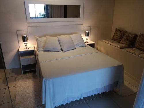 a bedroom with a white bed and a couch at Coco Beach Apart 5B in Natal