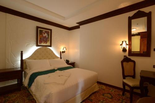 a bedroom with a bed with a mirror and a chair at Hotel Luna in Vigan
