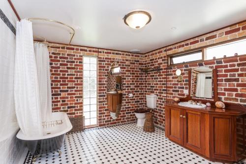 a bathroom with brick walls and a sink and a tub at Chianti Cottages in Torquay