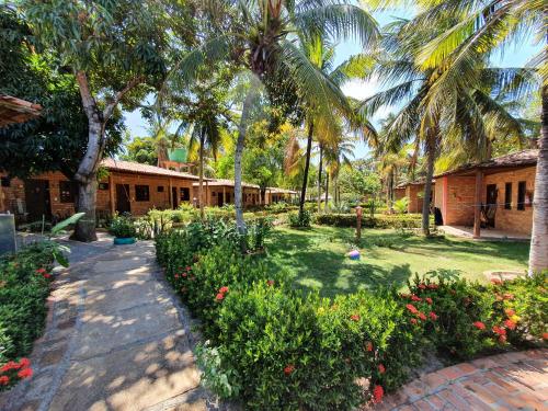a garden with palm trees and flowers in front of a building at Pousada do Riacho in Barreirinhas