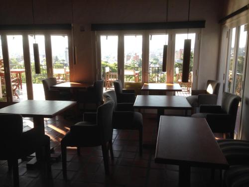 a restaurant with tables and chairs and windows at Casa Alta Hotel Boutique & Spa - Solo Adultos in Villa Carlos Paz