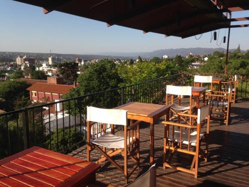 a deck with four chairs and a table and an umbrella at Casa Alta Hotel Boutique & Spa - Solo Adultos in Villa Carlos Paz