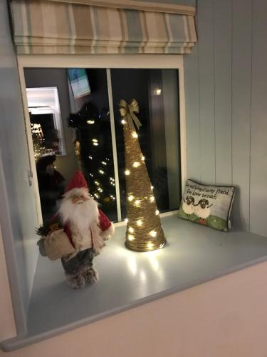 a window sill with a santa clause and a christmas tree at Toddys Cottage & Stables in Cavan