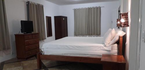 a bedroom with a bed and a dresser with a television at Pousada Vale do Luar in Canoa Quebrada