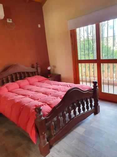 1 cama con edredón rojo en un dormitorio en Lago del bosque en Mar de les Pampas