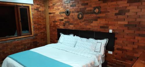 pared de ladrillo con cama en una habitación en Cabaña Rodamonte - Neusa, en Cogua