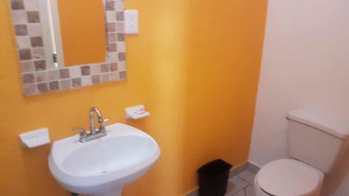 a bathroom with a white toilet and a sink at Posada la Natividad in Tepoztlán