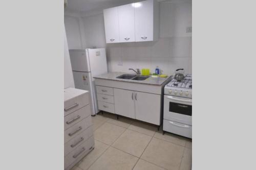 een witte keuken met een fornuis en een koelkast bij home rent in La Plata