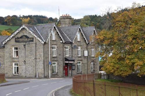 un antiguo edificio de piedra al lado de una carretera en The Llanelwedd Arms Hotel, en Builth Wells