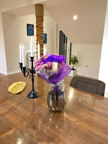 a vase with purple flowers and candles on a table at Bali Apartment in Belgrade