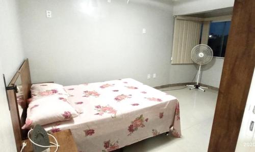 a bedroom with a bed with a pink blanket and a fan at Casa temporada Rio das Ostras - Garagem - Piscina - Wi-fi - Cozinha Completa - Sky e Netflix - Ar condionado in Rio das Ostras