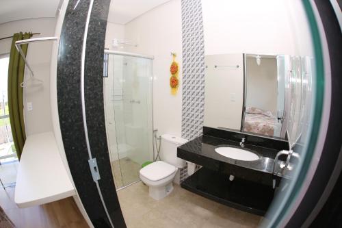 W łazience znajduje się umywalka, toaleta i lustro. w obiekcie Pousada Pérola Mineira w mieście Piuí
