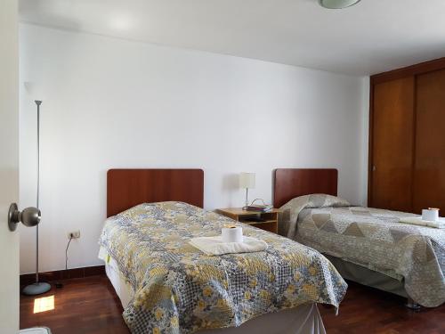 Un dormitorio con 2 camas y una mesa con toallas. en EL ENSUEÑO, en Lima