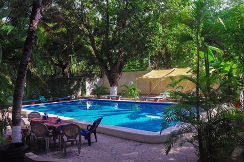 una piscina con tavolo, sedie e alberi di Hotel y Restaurante Rincón Familiar a La Libertad