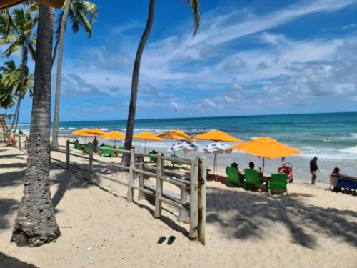 una playa con gente sentada bajo sombrillas y el océano en Praia dos Carneiros Flat 207 A - Carneiros Beach Resort, en Tamandaré
