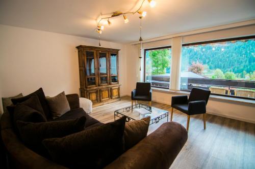 a living room with a couch and a large window at Hotel Berghof in Nesselwängle