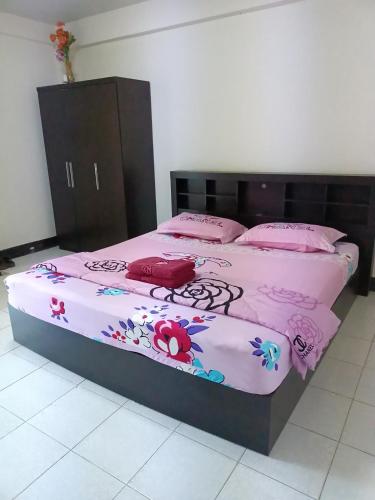 a bed with pink sheets and flowers on it at ทองธิดาอพาร์ทเม้นท์ in Phitsanulok