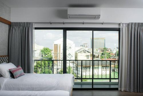 um quarto de hotel com uma cama e uma grande janela em Himku Hotel - adult only em Chiang Mai