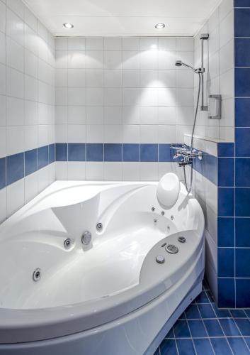 a white tub in a bathroom with blue tiles at Hotel Seurahuone Riihimäki in Riihimäki