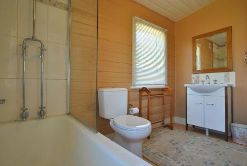 a bathroom with a toilet and a tub and a sink at Cooma Cottage in Cooma