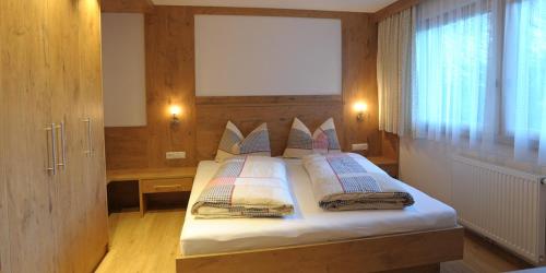 a bedroom with a bed with white sheets and pillows at Texas Longhorn Ranch Neumannhof in Cadipietra