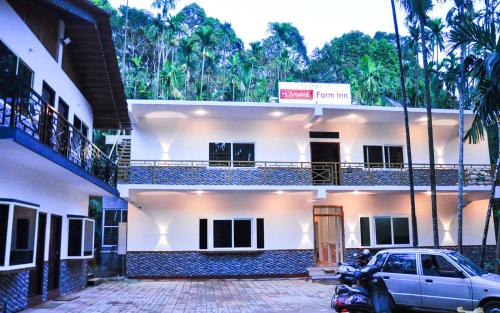 a white house with a car parked in front of it at Hosamane Farm Inn in Sringeri