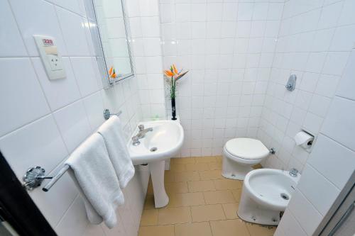 uma casa de banho branca com um lavatório e um WC em Arcadas Hotel em Caçapava