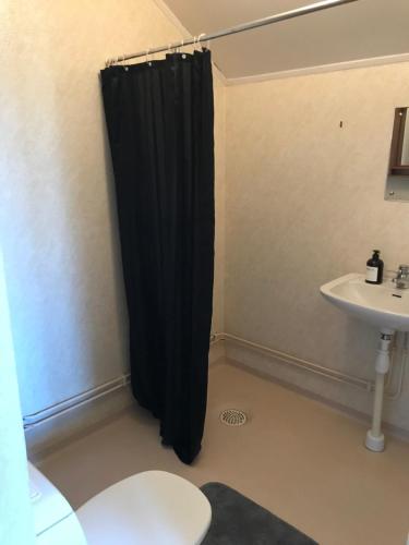 a bathroom with a black shower curtain next to a sink at Säfsen in Fredriksberg