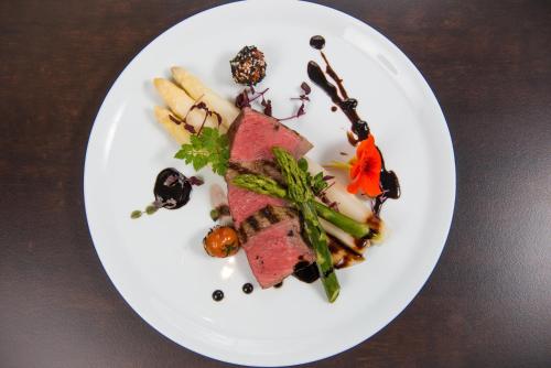a white plate with meat and vegetables on a table at Hotel Volapük in Konstanz