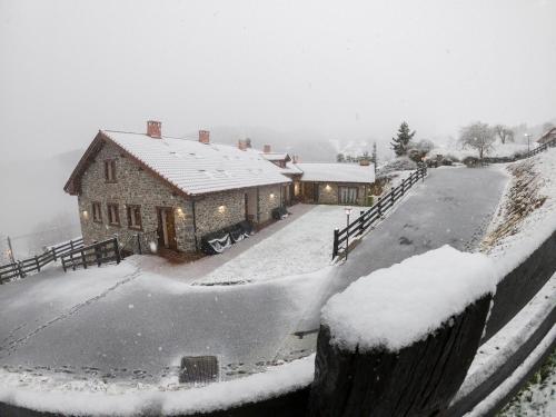 a house covered in snow in front of a house at Apartamentos Los Picos de Europa in Colio