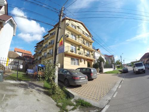 un bâtiment jaune avec des voitures garées devant lui dans l'établissement Vila Cristal, à Băile Felix