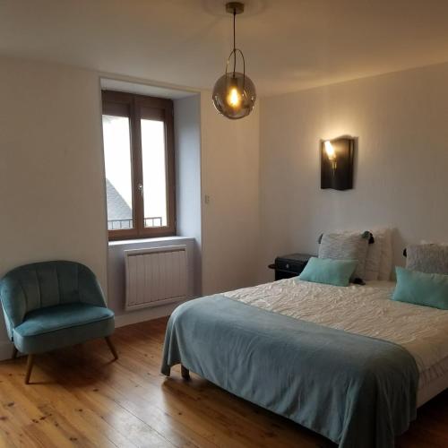 une chambre avec un lit, une chaise et une fenêtre dans l'établissement Le gîte de la Vieille Eglise de Coussergues, à Coussergues