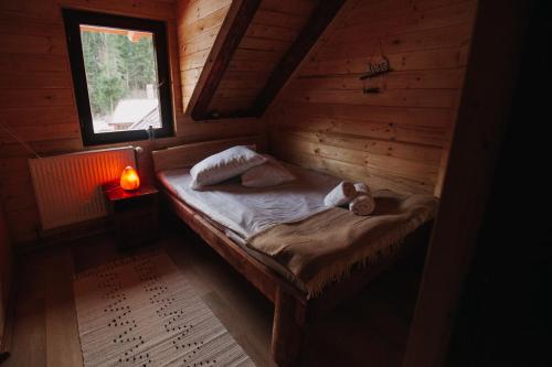 a small bed in a wooden room with a window at Csángó Panoráma in Valea Rece