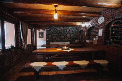 a dining room with a table and a stone wall at Csángó Panoráma in Valea Rece