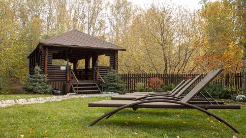 a group of chairs sitting in the grass in front of a cabin at Котедж-парк Славна in Okhtyrka