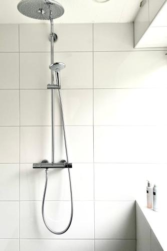 a shower in a bathroom with white tiles at Alibi aan Zee in Wijk aan Zee