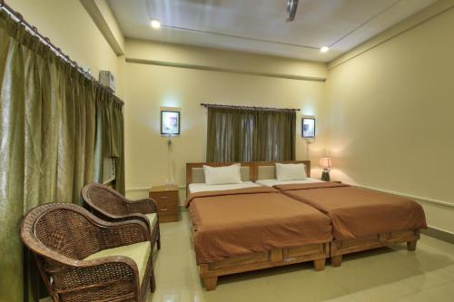 a bedroom with a large bed and two chairs at Harmony House - A Boutique Hotel in Guwahati