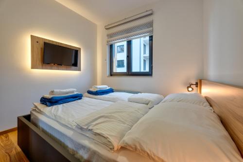 兹拉蒂博尔Zlatibor apartman Asteri的一张带白色床单的大床和平面电视