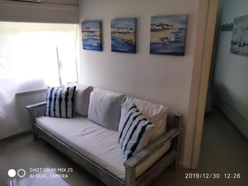 un sofá en una habitación con fotos en la pared en Apartamento Marina de roosvelt con piscina climatizada, en Punta del Este